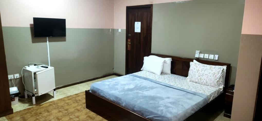 a bedroom with a bed and a flat screen tv at NHYIRA Hotel in Sekondi-Takoradi