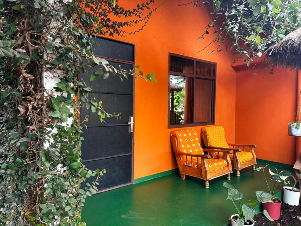 an orange house with a chair and a window at East Homestay in Boma la Ngombe