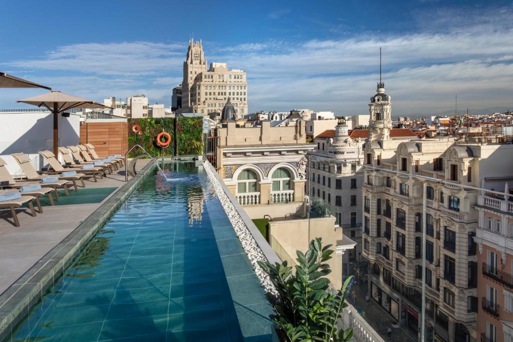 a pool on the roof of a building with buildings at Catalonia Gran Vía Madrid in Madrid