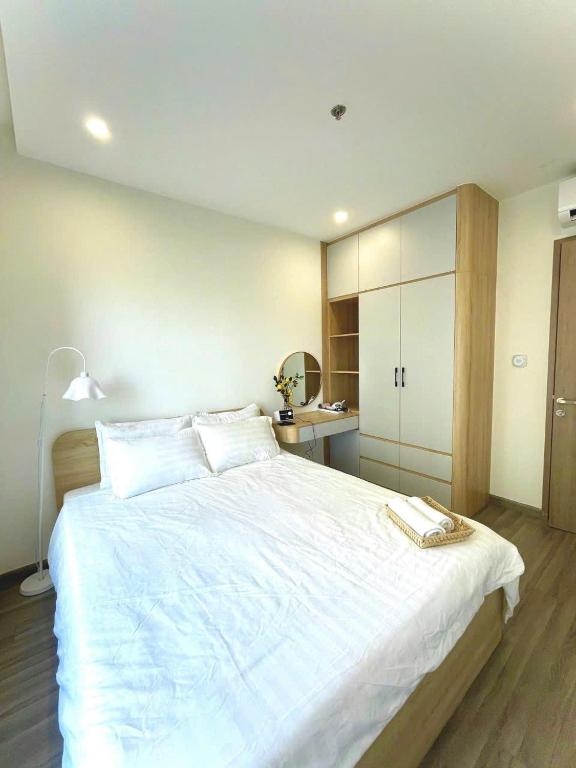 a bedroom with a large white bed and a desk at Toà gh6 in Gò Công