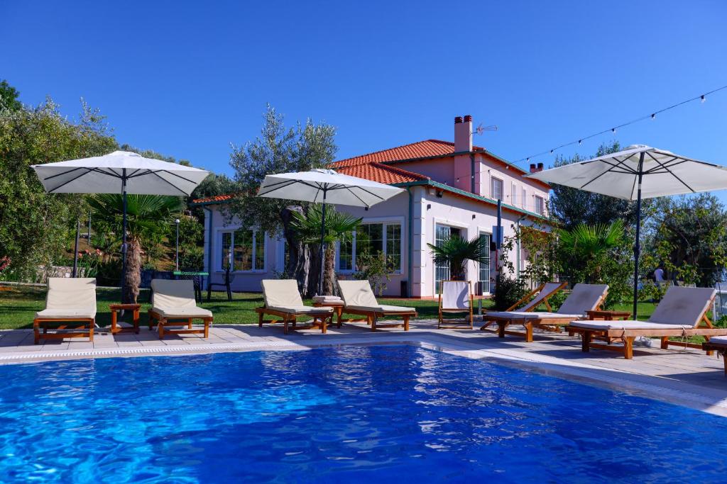 a pool with chairs and umbrellas next to a house at Agroturizem Bylis in Hekal