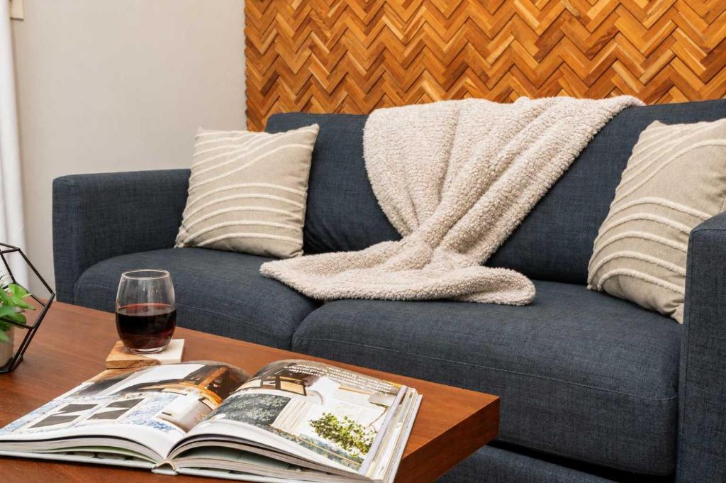 a couch with a book and a glass of wine on a table at Jennifer's Modern Federal Hill Apt w Private Deck in Providence
