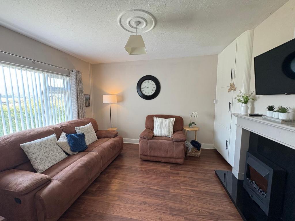 a living room with a couch and a clock on the wall at Teach Duff in Clonmany