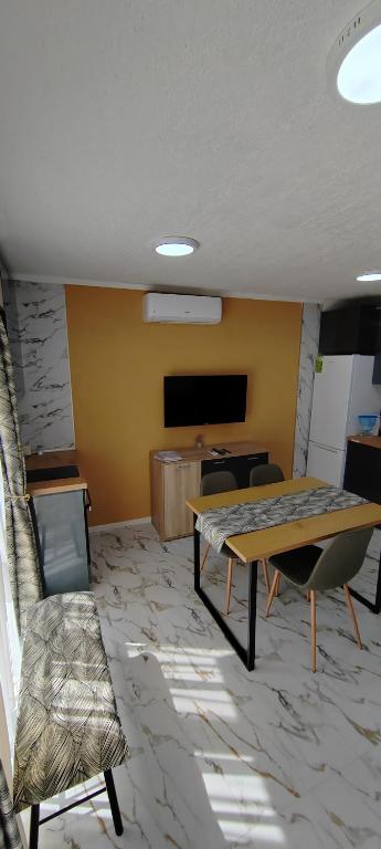 a room with a table and chairs and a tv at Тера Лакшъри Суит in Asenovgrad