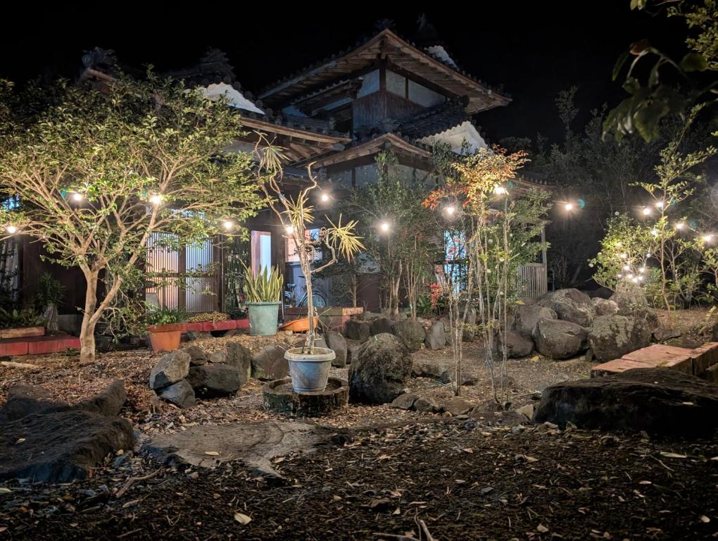 a garden with trees and lights in front of a house at Ikada in Amami