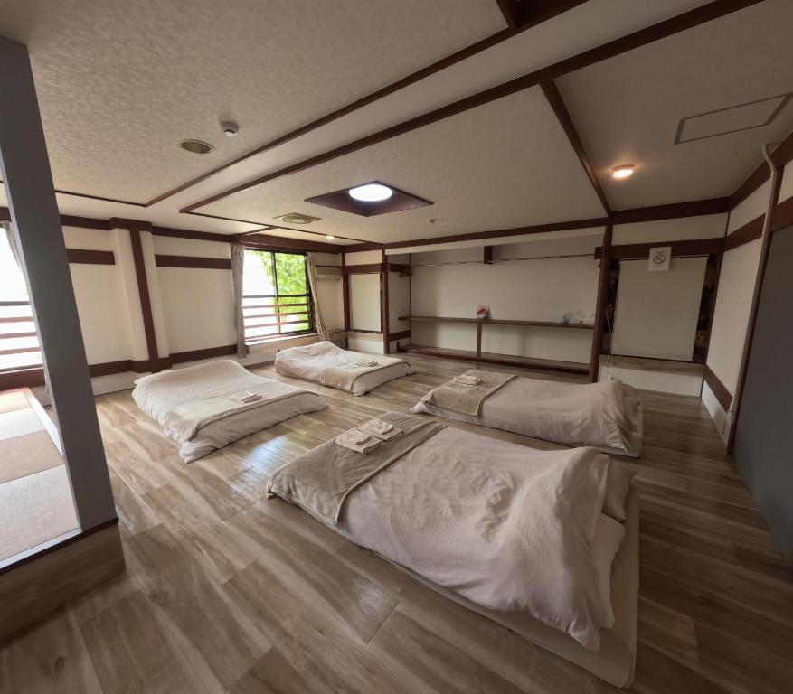 three beds in a room with wood floors at Aizuwakamatsu Piacere in Aizuwakamatsu