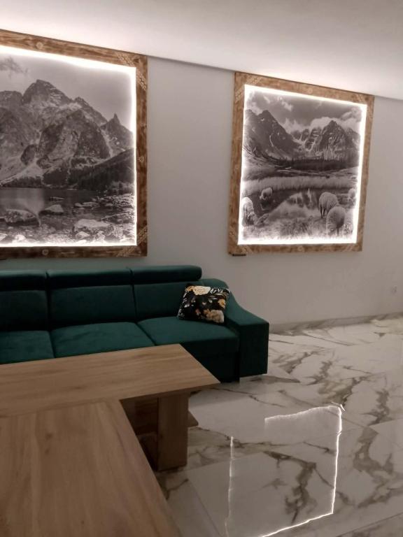 a living room with a green couch and two pictures on the wall at Wiyrchowianka in Gliczarów Górny