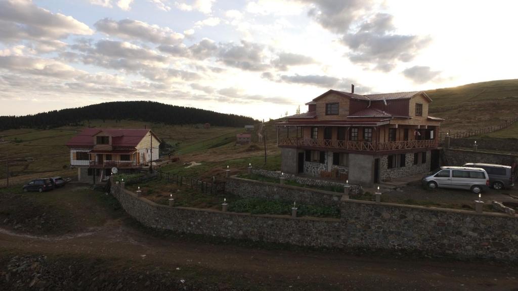 une maison sur une colline avec des voitures garées devant elle dans l'établissement Yildirim Aile Pansiyonu, à Sultan Murat Yaylasi