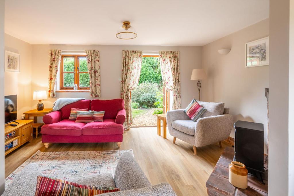 a living room with a red couch and two chairs at Acorn House in Briston