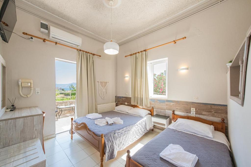 a hotel room with two beds and a balcony at Bikakis Family Apartments in Kissamos