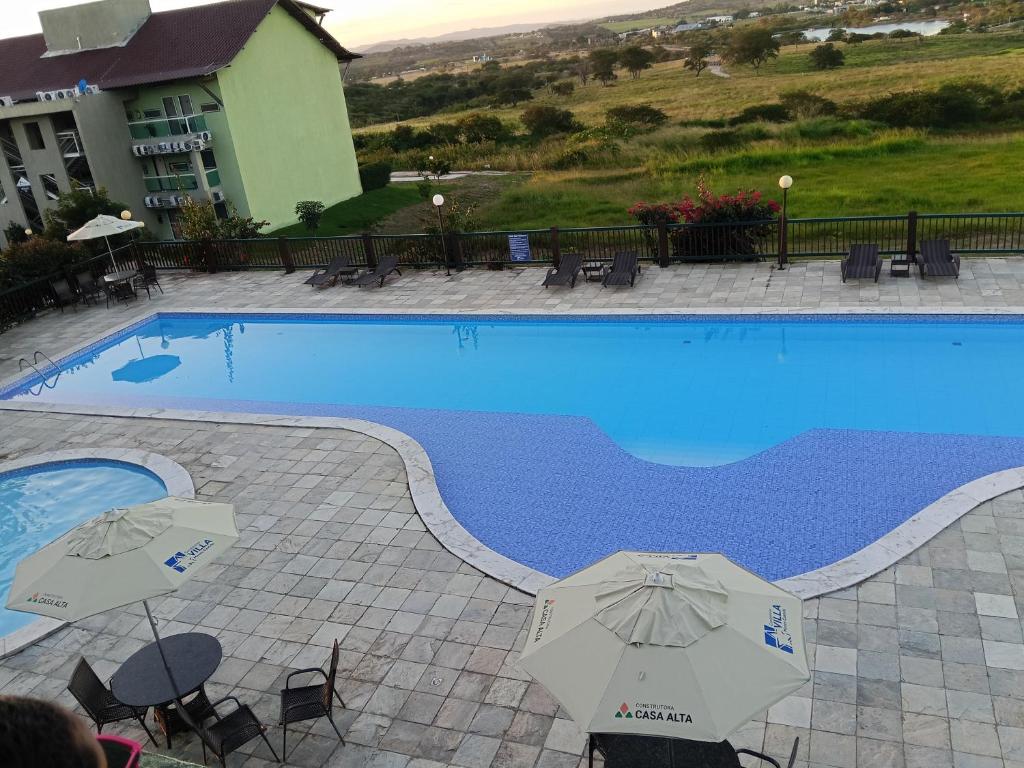 a swimming pool with umbrellas next to a hotel at Flat em Gravatá -Villa Monte Castelo - 2 quartos- Ao Lado da Área de Lazer e das piscinas in Gravatá