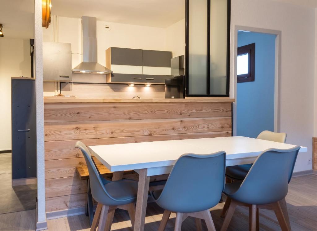 a kitchen with a table and blue chairs at Appartement charmant à Briançon de 40 m² avec balcon in Briançon