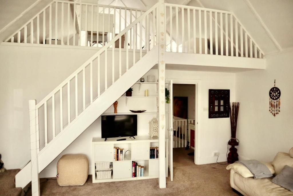 a white staircase in a living room with a tv at Serenity Heights in Westgate-on-Sea