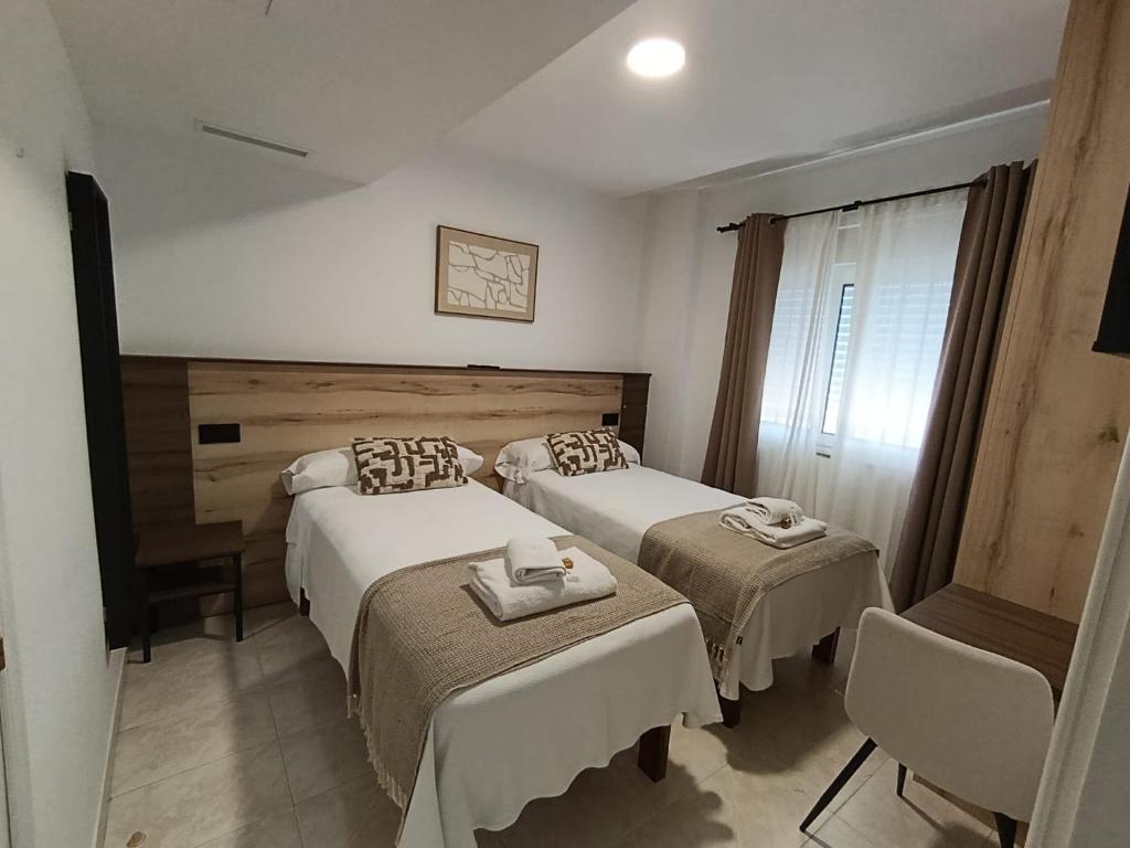 a hotel room with two beds and a window at Pensión Pastoriza in Vimianzo