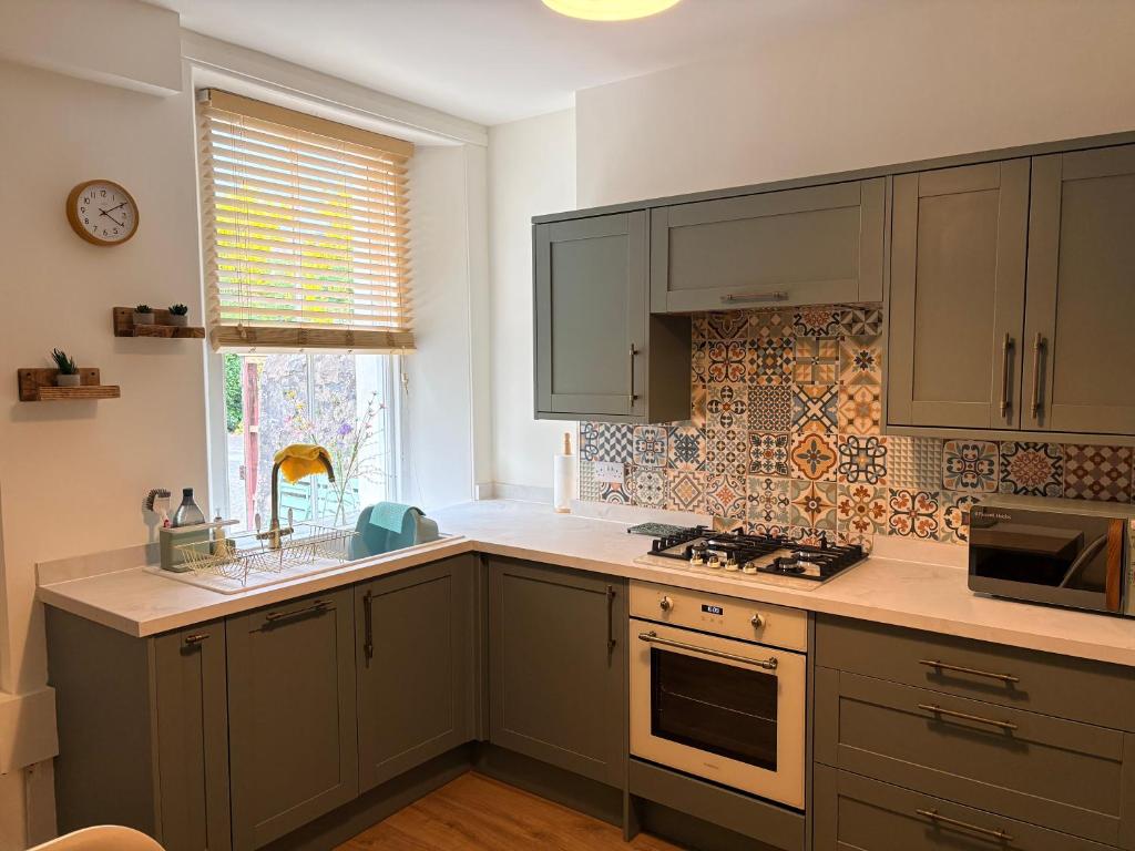 a kitchen with green cabinets and a sink and a window at Myrtlebank in Pitlochry