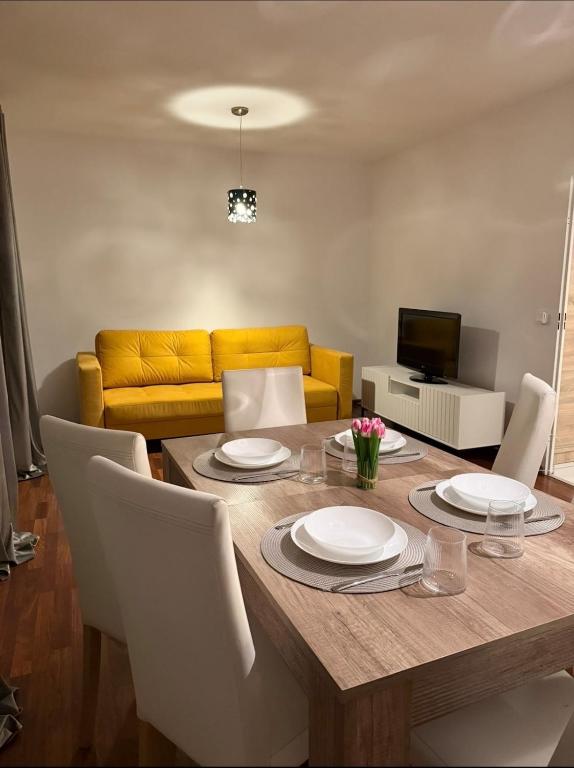 a dining room table with white chairs and a yellow couch at Apartament Miejski Azyl in Rybnik