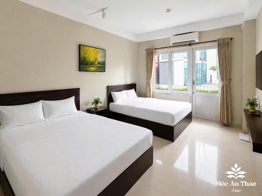 a hotel room with two beds and a window at Mộc An Thảo Hotel in Quy Nhon