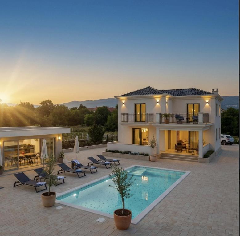 a villa with a swimming pool at sunset at Villa Decima near Split - Heated Pool, Tennis Court & Billiards in Dicmo