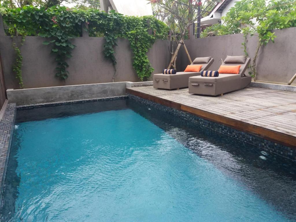 a swimming pool with two lounge chairs on a wooden deck at Anshel Hotel Seminyak in Seminyak