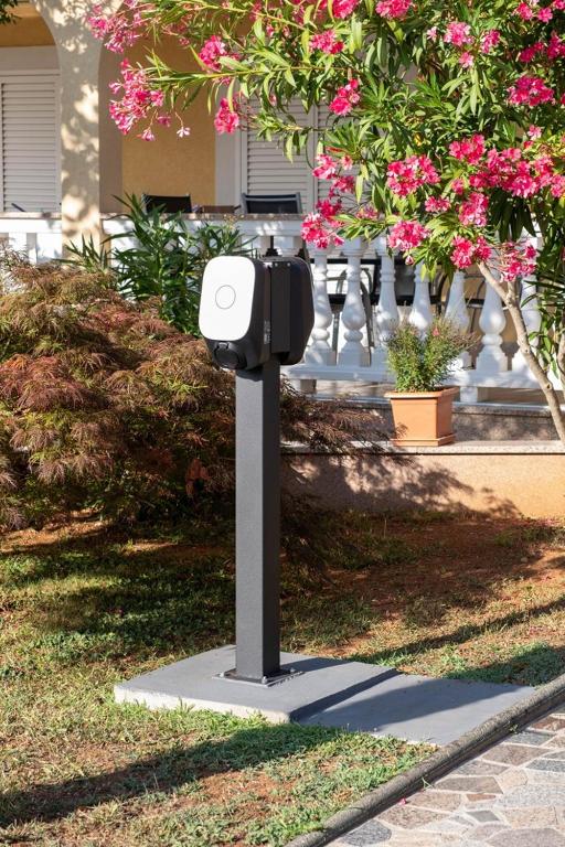 a parking meter in the grass with pink flowers at Apartments Šerbečić in Malinska
