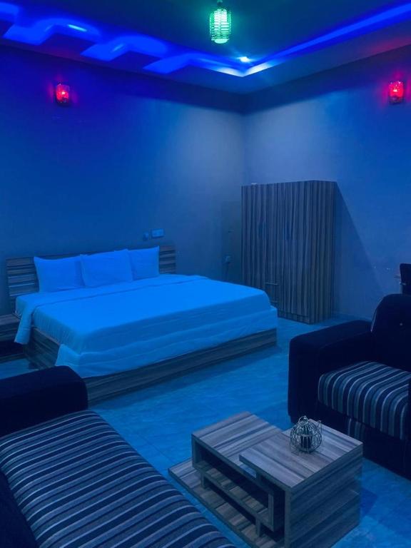 ein Schlafzimmer mit zwei Betten, einer Couch und blauen Lichtern in der Unterkunft Larrydam hotel in Ilesa