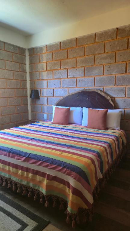 ein Schlafzimmer mit einem großen Bett und einer Backsteinwand in der Unterkunft Hotel Jabal Inn in Tixmucuy