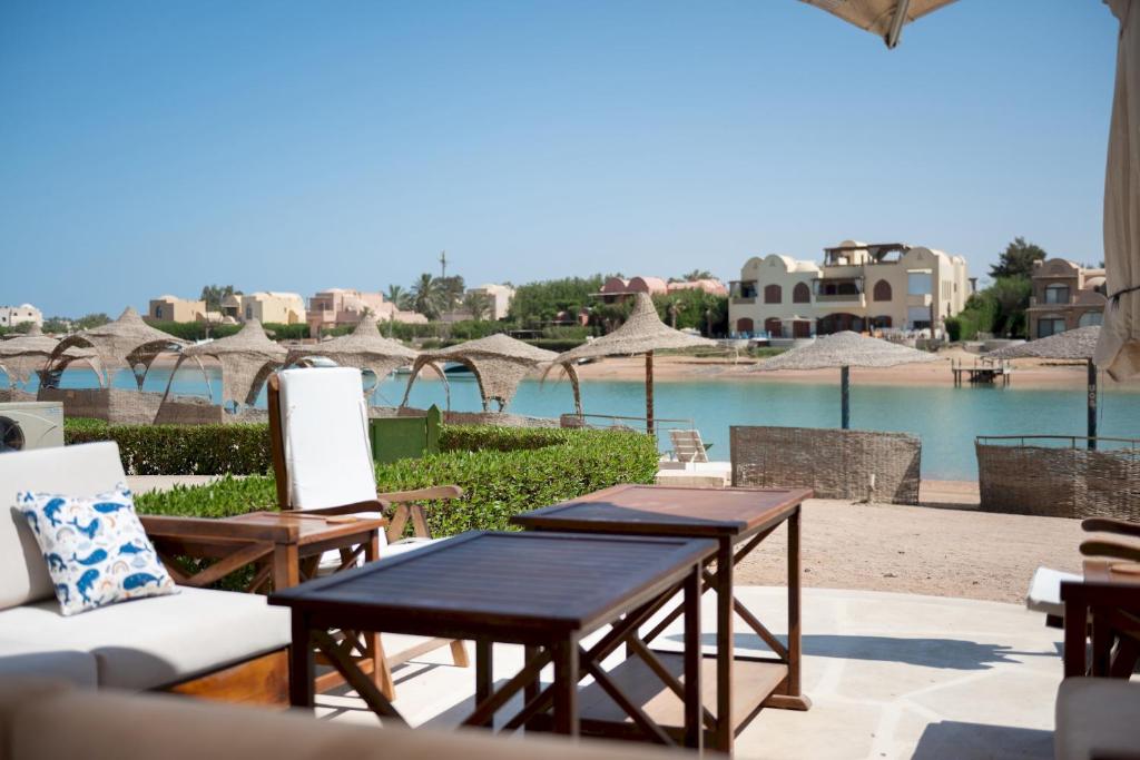 a patio with tables and chairs and a body of water at VESTA - El Gouna Residence in Hurghada