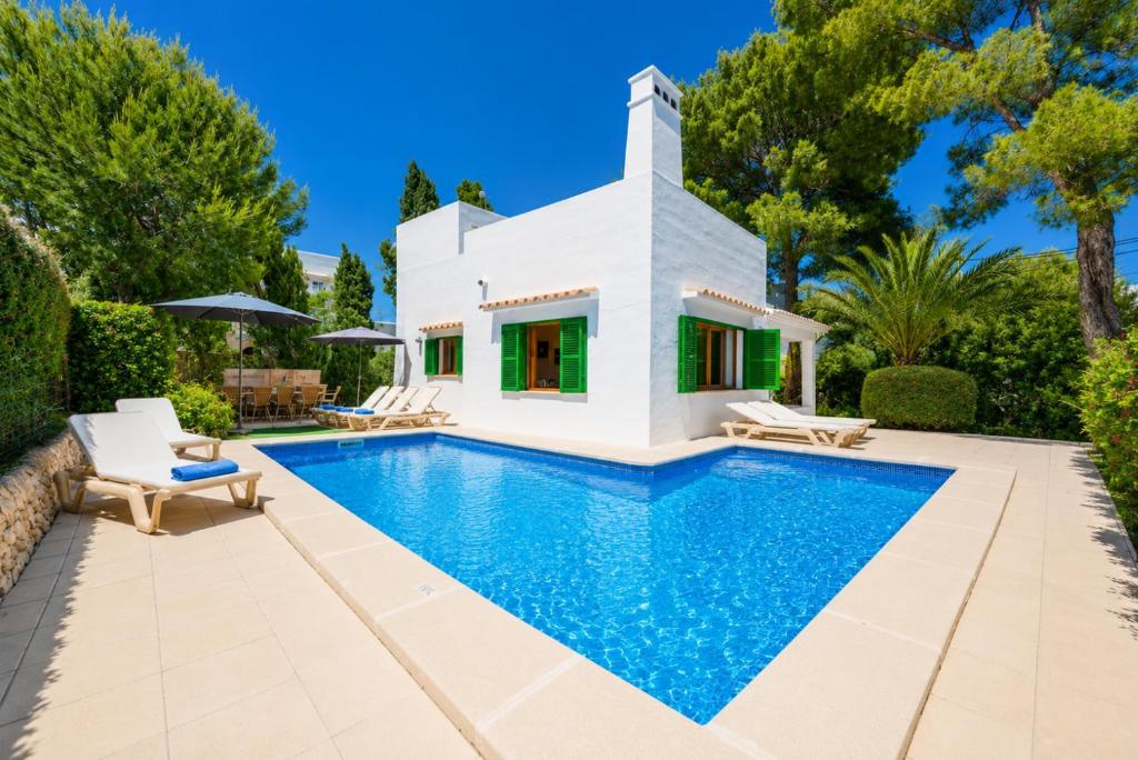 a villa with a swimming pool in front of a house at Villa Binimelis in Cacla D'or