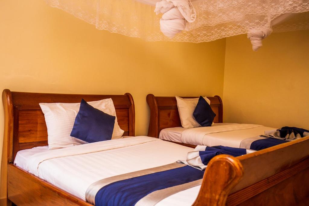 two beds sitting next to each other in a room at Sandton hotel kasese in Nalakonge