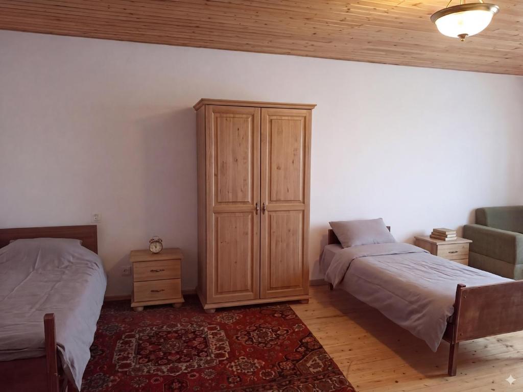 a bedroom with two beds and a wooden cabinet at HUSAYN HoSTEL in Xirdalan