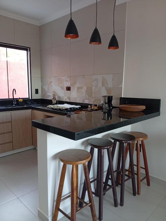 a kitchen with a island with three bar stools at Casa da Serra in Serra Negra