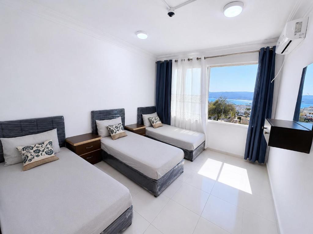 a bedroom with two beds and a large window at Nice Apartment with Sea View in Aqaba