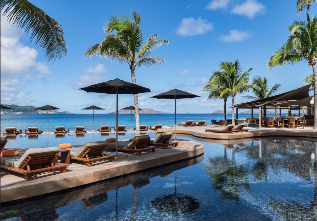 a resort swimming pool with chairs and umbrellas at Hotel Christopher Saint Barth in Pointe Milou
