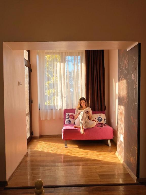 a woman sitting on a couch reading a book at Anna ByTheSea By iVAVev in Eforie Sud