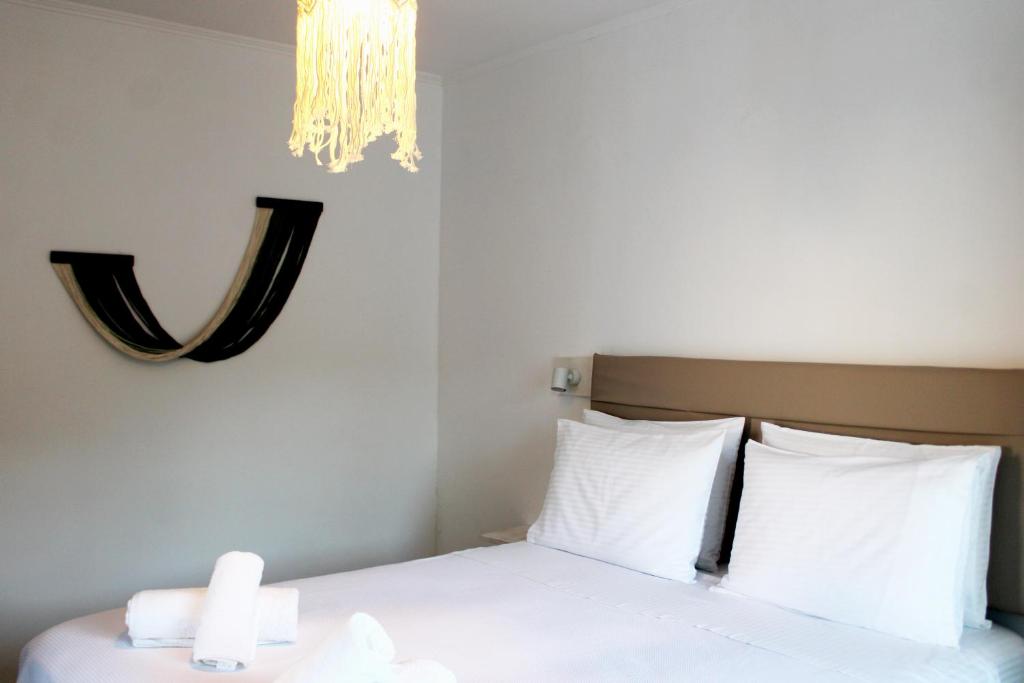a bedroom with a bed with white sheets and a chandelier at Lyra Apartments Tilos in Livadia