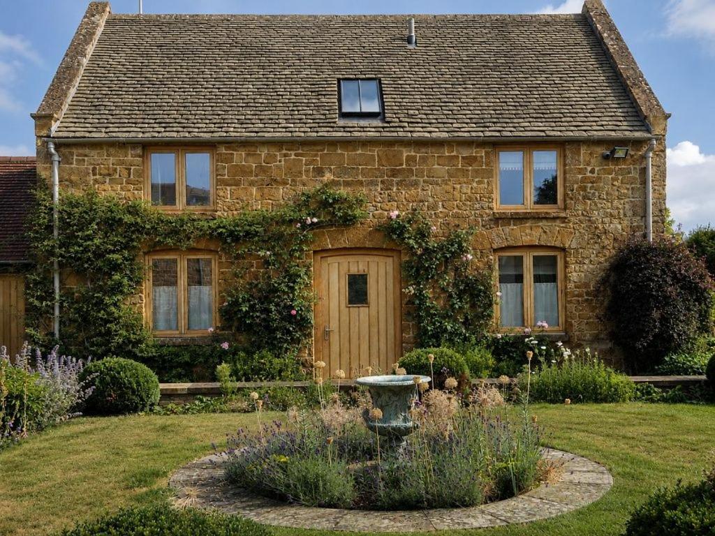 a brick house with a garden in front of it at Hobbs Hole Cottage in Great Tew
