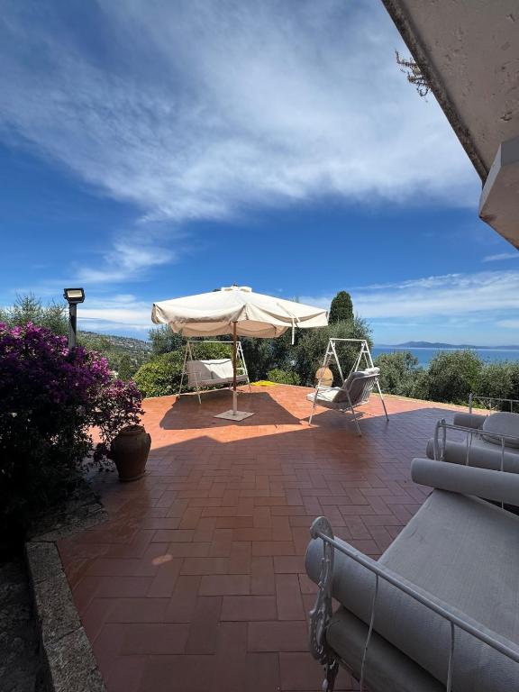 a patio with a white umbrella and a chair at Villa Maria Marcella in Porto Santo Stefano