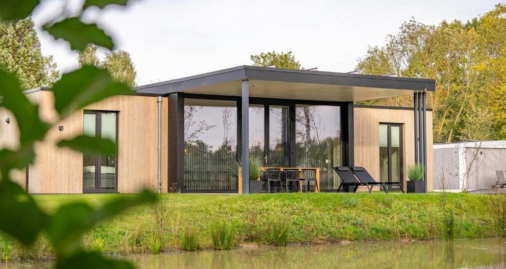 a small house with a roof on top of a field at Forest Lodge 6 persons #624 in Maasbree