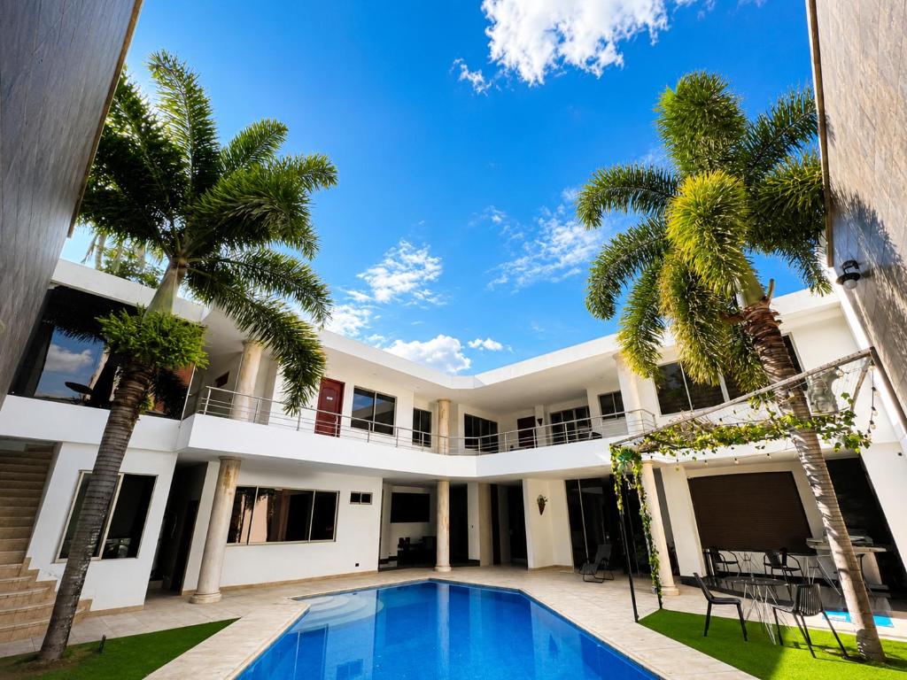 a villa with a swimming pool and palm trees at Espectacular, Casa Vacacional Jpol in Cali