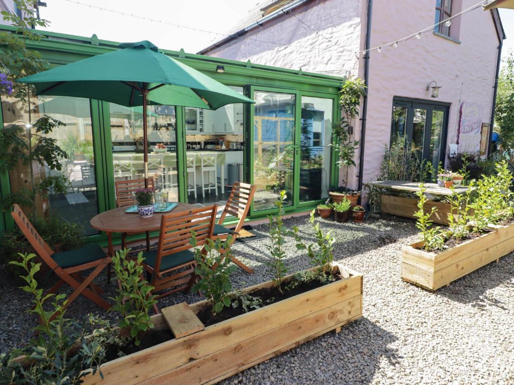 a patio with a table and an umbrella at The Garden Rooms in Narberth