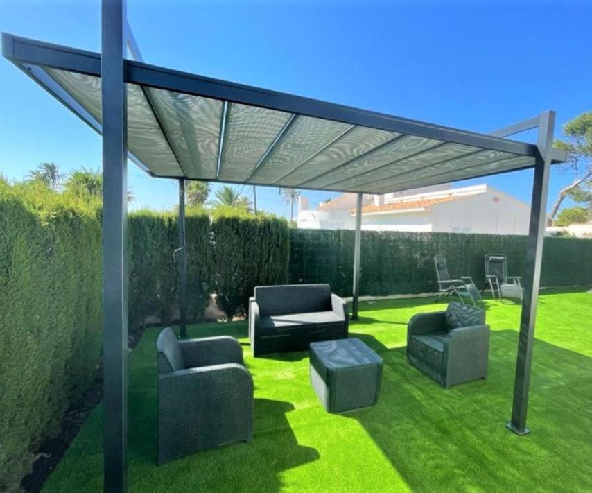 a pergola with couches and chairs on a lawn at Chalet Almadraba- Turistika in Denia