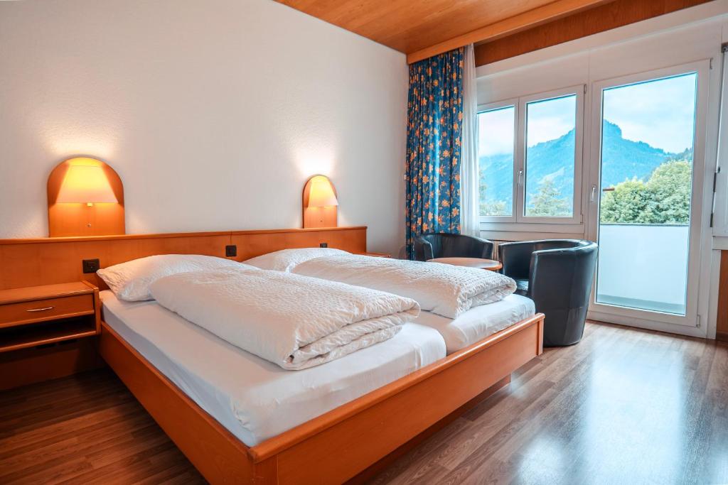 a bedroom with two beds and a large window at Parkhotel Bellevue Budget in Lenk
