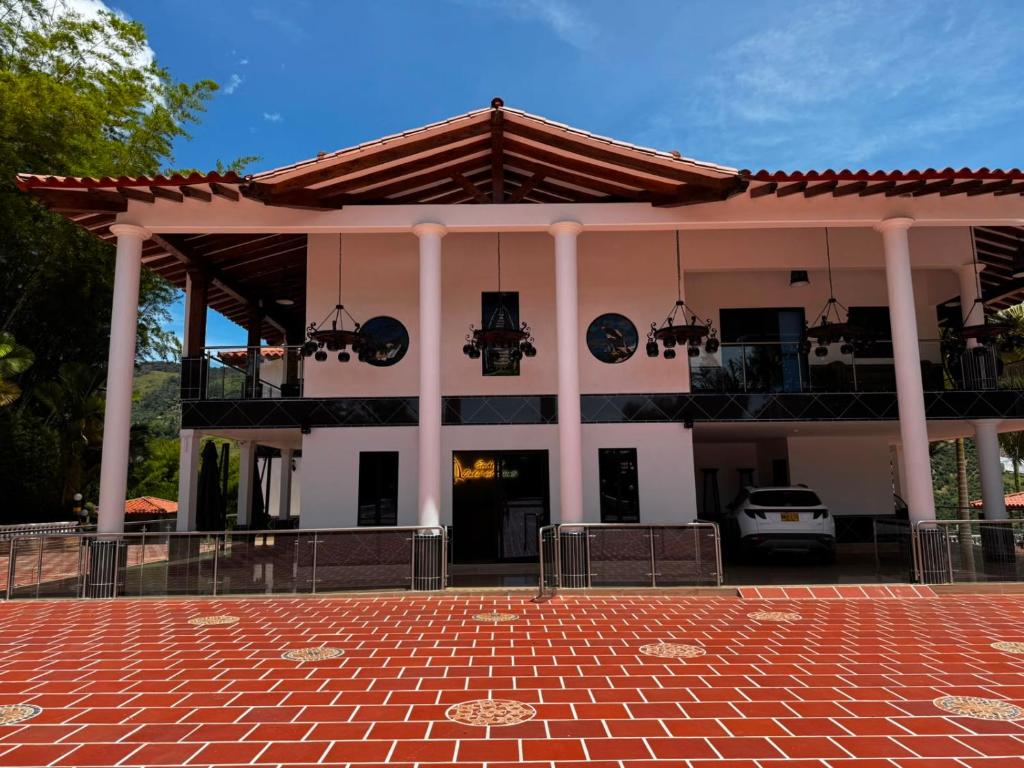 a large white building with a red brick patio at Ecohotel Dubai del Oriente in El Peñol