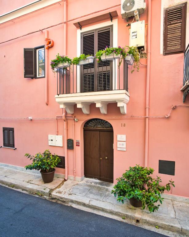 a pink building with a balcony and a door at Airport Palace Cinisi in Cinisi