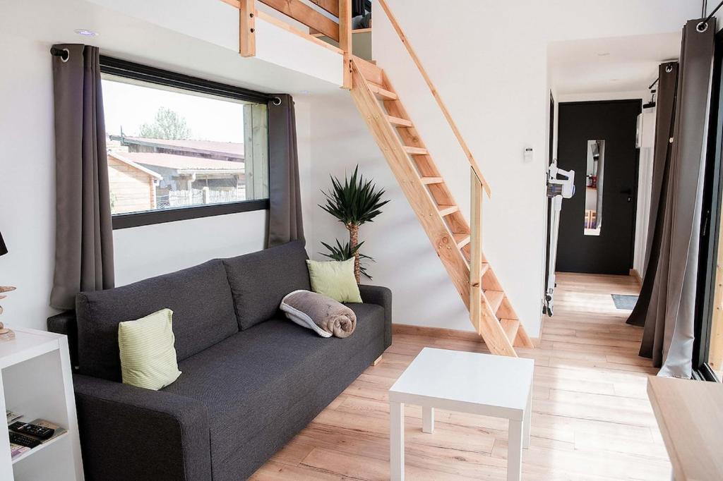 a living room with a couch and a stair case at Les Tiny d'Aureilhan avec Jacuzzi privatif in Aureilhan
