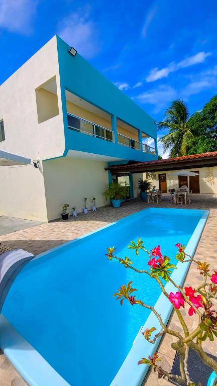 a villa with a swimming pool in front of a house at Pousada Donna Maraka in Porto De Galinhas