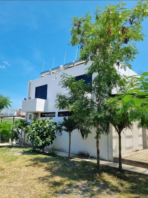 a white building with trees in front of it at Villas La Vista in Tuxpan de Rodríguez Cano
