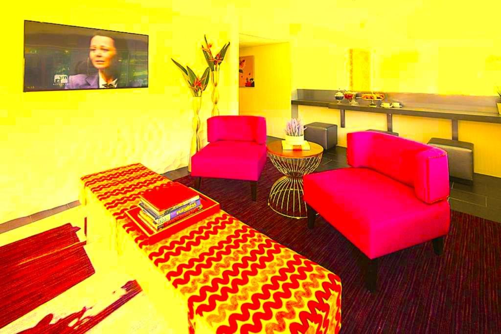 a living room with two red chairs and a table at Hotel Kalika Inn in Dhanbād