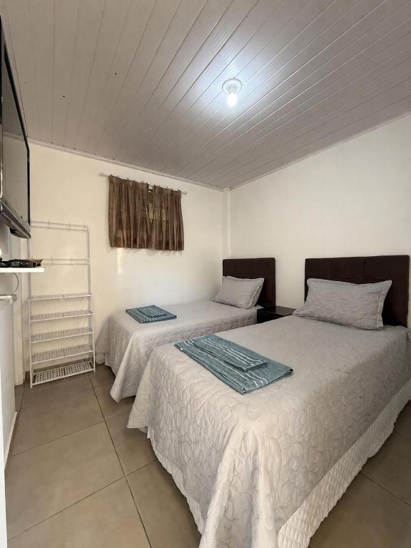 a bedroom with two beds with white sheets at Studio Planejado no Centro de Campos Novos in Campos Novos
