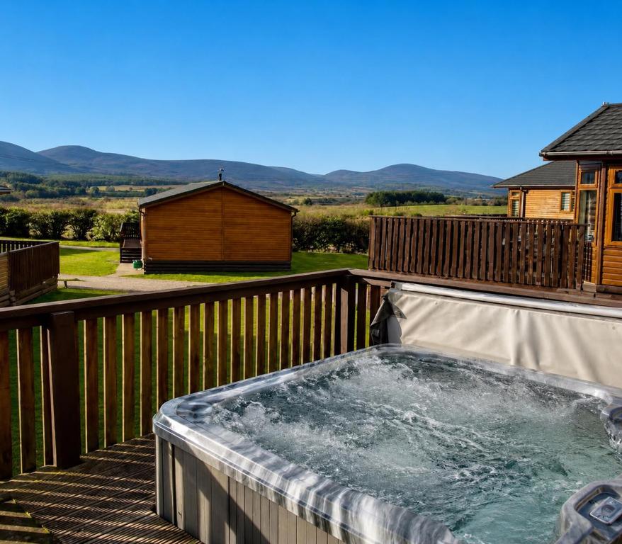 a hot tub on the deck of a house at Hepburns Lodge 19 in Strachan